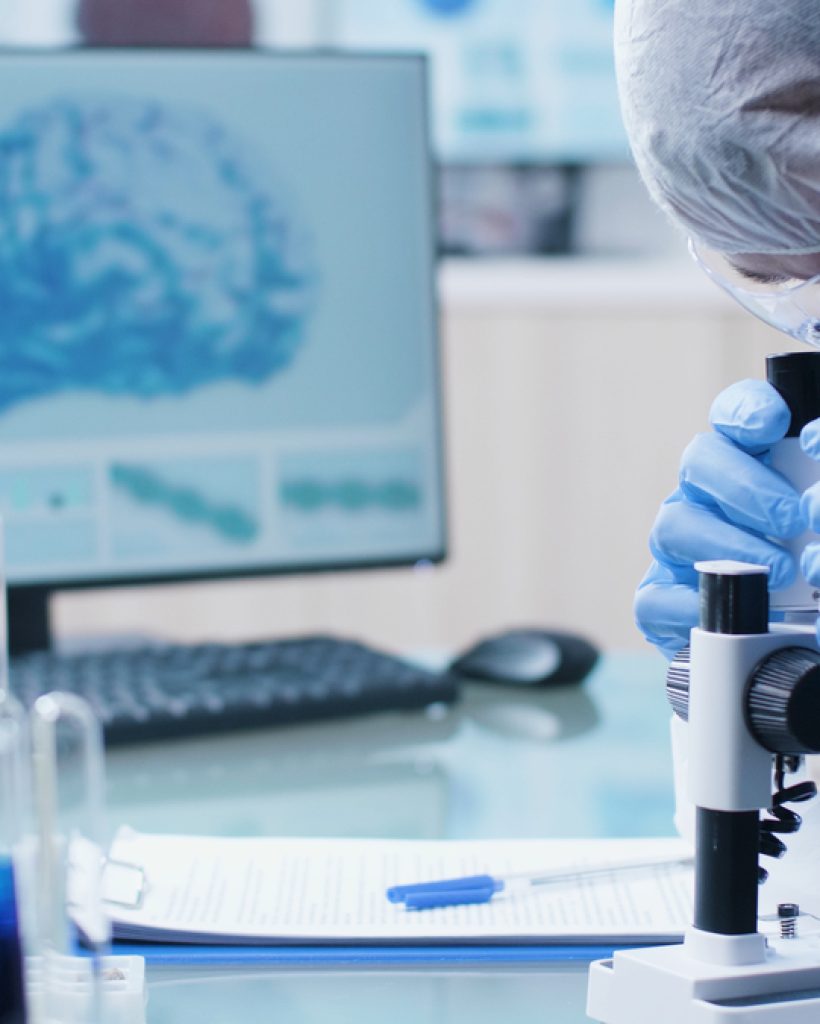 Scientist chemist researcher doctor analyzing dna sample using medical microscope developing vaccine against coronavirus during biochemistry experiment in hospital laboratory. Medicine concept